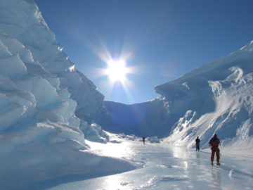 A group of people riding skis down a snow covered slope.