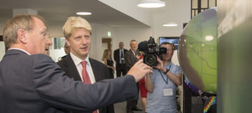 Jo johnson wearing a suit and tie holding a cell phone.