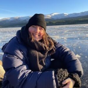 A man and woman sitting next to a body of water