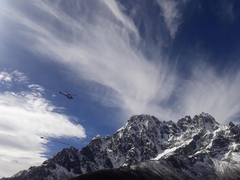 A helicopter flying through the air on top of a mountain