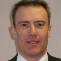 A man wearing a suit and tie smiling at the camera.