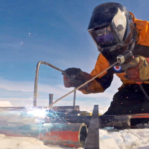 A person welding in an icy landscape