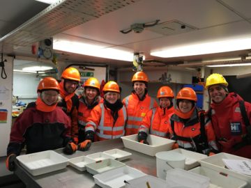 Angelika brandt et al. standing around a table.