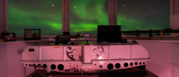 A green aurora out of the windows of a research station