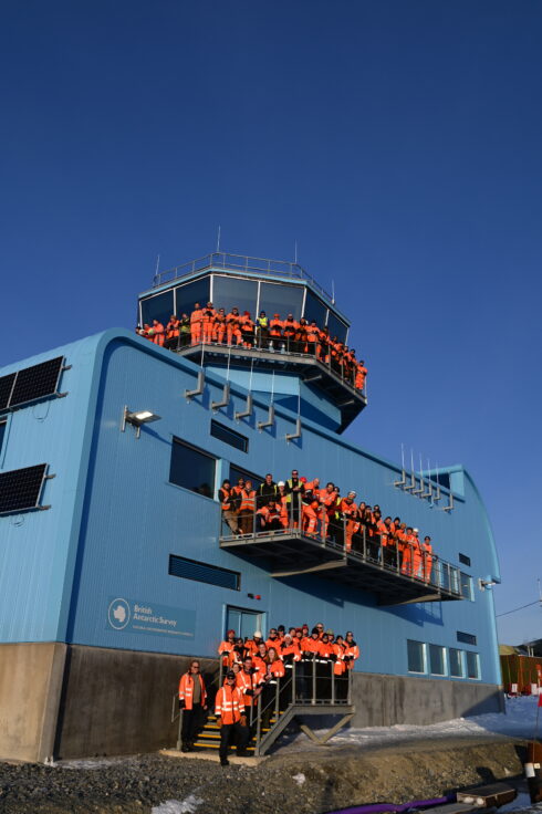 People who worked on the Discovery Building's construction posing for a photograph on the steps, balcony and control tower of the Discovery Building.