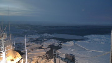 A ship in a body of water with a mountain in the background.