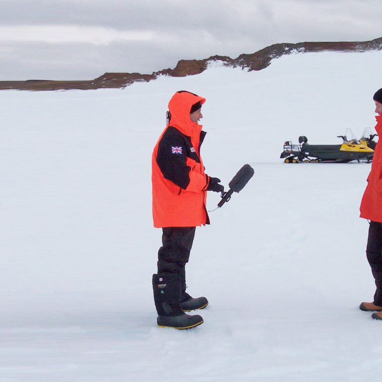 A film crew interviewing a man in an icy landscape