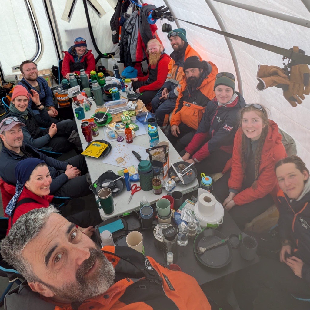 A group of people posing for the camera in deep field tent