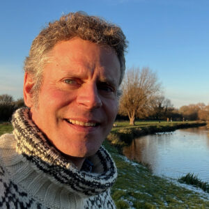 Markus standing next to the river Cam in the light of the setting sun