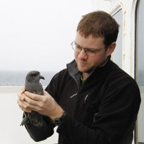 A man standing next to a window.