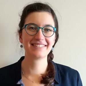 A woman wearing glasses and smiling at the camera.