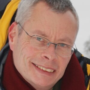 A man wearing glasses and smiling at the camera.