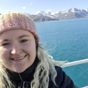 A woman smiling next to a body of water