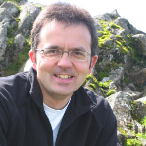 A man standing in front of a large rock.