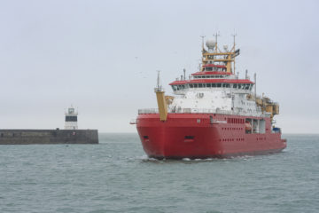 Large red ship arrives into a port