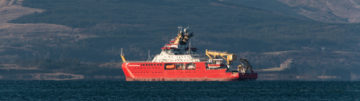 A large ship in a body of water with a mountain in the background