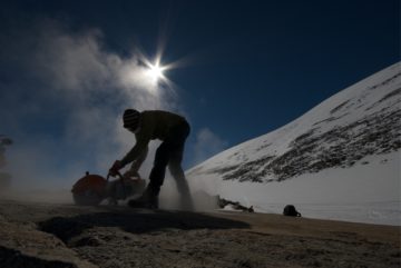 A man riding a snowboard down a snow covered slope.